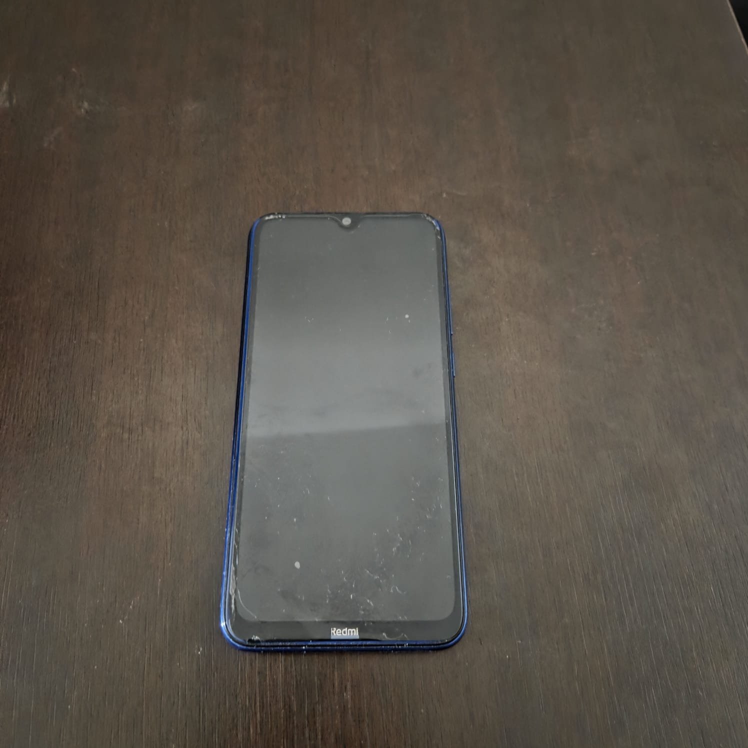 Smartphone preto sobre mesa de madeira escura