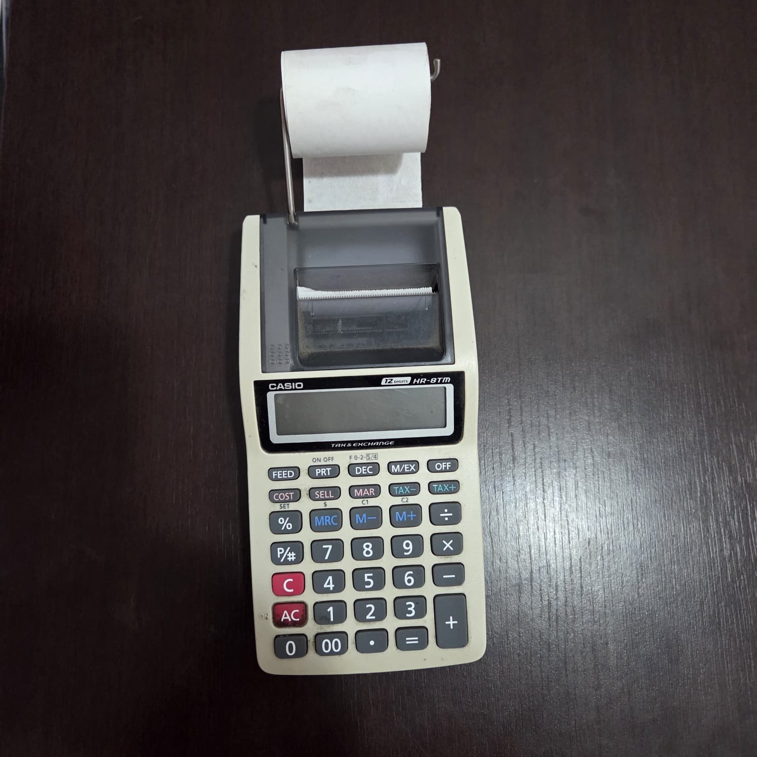 Calculadora Casio com impressora de papel sobre mesa